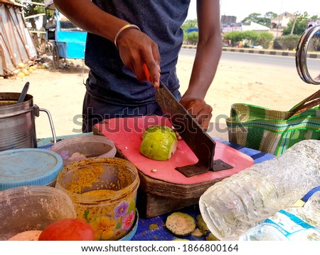 picture of vendor cutting guava with blade for making chaat with gren chilly paste, red chilli powder, chat masala, salt, black salt and lemon.