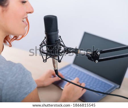 Rear view of woman broadcasting online radio on laptop. The girl is recording a podcast on her channel