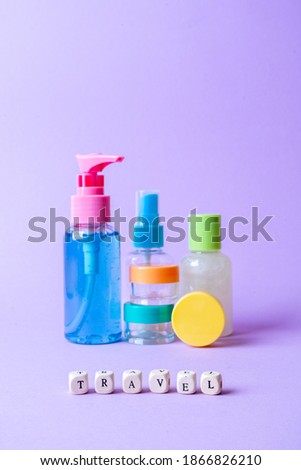 Set of full plastic travel bottles on lavender background. Travel kit with approved for airplane hand luggage bottle container size. Travel containers with colorful tops.