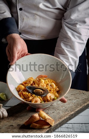 Chef proudly presenting spanish paella valenciana - spanish cuisine
