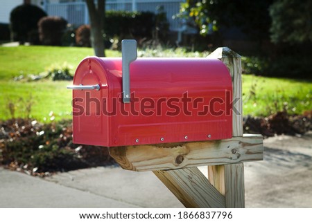 Red rural mailbox on a brown wooden post with silver flag raised close up Royalty-Free Stock Photo #1866837796