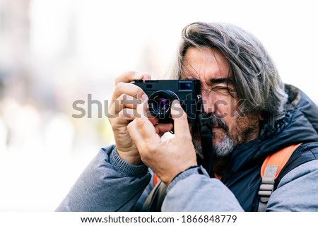 Adult man with white hair taking a picture with a retro camera