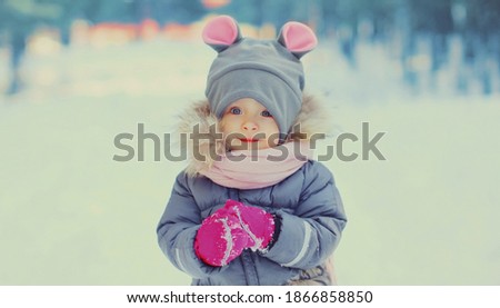 Portrait of cute happy little child in winter over snowy background