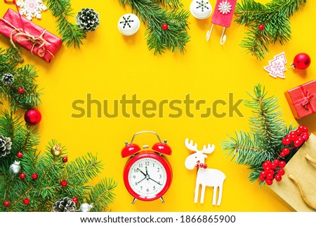 Christmas background frame, Christmas card. Holiday decorations, fir branches, gifts and red vintage alarm clock on a yellow background, top view, copy space	
