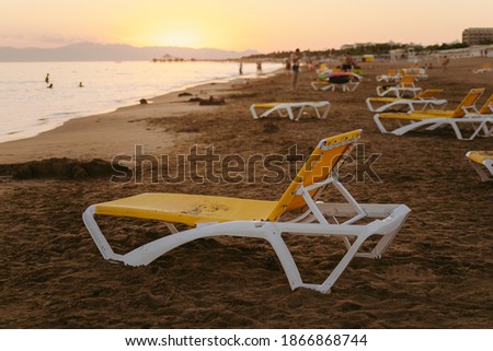 Scenic sunset on summer beach and small silhouettes of people in background.