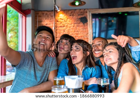 A cheerful group of friends taking a selfie while having fun in a pub.