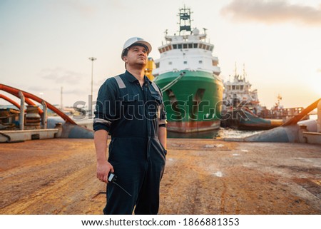 Marine Deck Officer or Chief mate on deck of offshore vessel or ship , wearing PPE personal protective equipment - helmet, coverall. Ship is on background Royalty-Free Stock Photo #1866881353