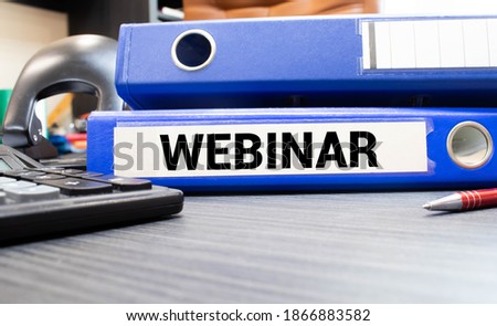 The word Webinar is written in black letters on yellow note paper. A yellow pen is embedded in the background of the blue diary.
