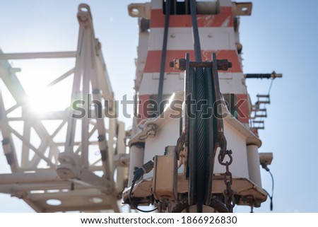 Wire rope sling and hoisting equipment part of lifting crane in heavy industry, photo contained sun light's flare. Industrial object photo, selective focus at the sling part in sheave wheel. 