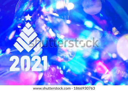 Christmas background-garlands with colorful lights on a decorated Christmas tree, bokeh, Happy New Year 2021 colored symbol and text in trendy flatten style design for seasonal holidays flyers