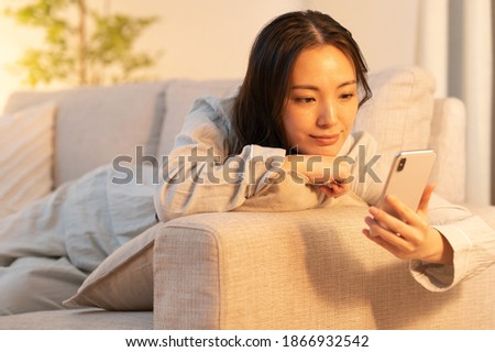 Asian woman relaxing indoors and touching her cell phone