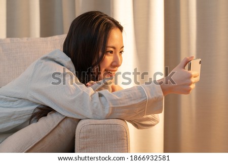 Asian woman relaxing indoors and touching her cell phone