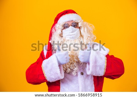 Real Santa Claus on yellow background, wearing protective mask against the covid19. Christmas with social distance. Covid-19