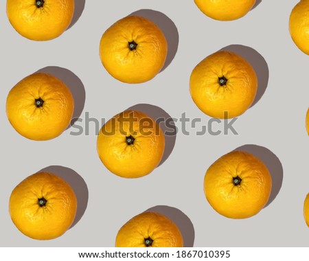 A pattern of big orange mandarins with a pronounced shadow on a beige background. Mandarin set, healthy food.