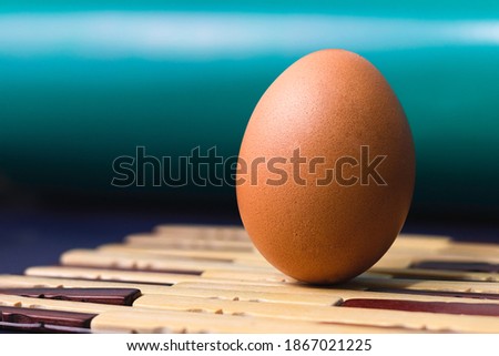 Brown egg on wooden mat

Photo of  a perfectly sharp brown nutritious raw egg with a complementary color on the background