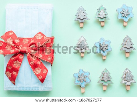 medical protective face masks as a gift with a red ribbon on a green background. Christmas and New Year 2021 decor painted firs and snowflakes. Holidays self-isolation and coronavirus pandemic concept