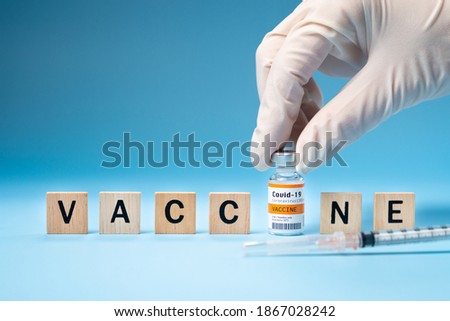 Promising Covid-19 Vaccine concept. Hand of a researcher take a 2019-nCov vaccine vial with wooden alphabet letters "VACCINE". Candidates, Authorized, Volunteers, Global trial, Hope, Successful. Royalty-Free Stock Photo #1867028242