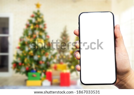 Close-up of female use smartphone blurred images with Colorful balls on Green Christmas tree background Decoration During Christmas and New Year.