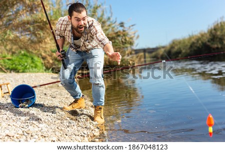 Happy fisherman pulls fish out of the river. High quality photo