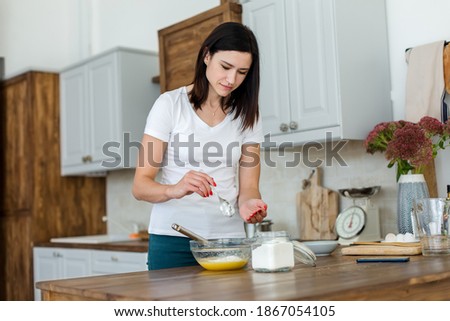Girl prepares a meal, whisking the mixture with flour with a whisk.