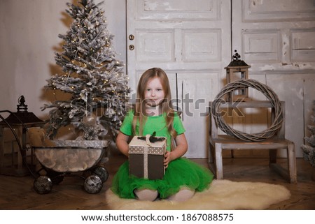 Cute smiling six-year-old girl with Xmas gift about Christmas tree. Child in interior living room for New year. Image for site background. Concept happy holidays together, love and trust. Copy space