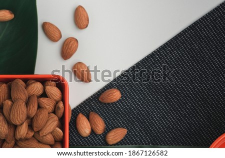 The almonds are in an orange cup. Almond concept with copyspace.