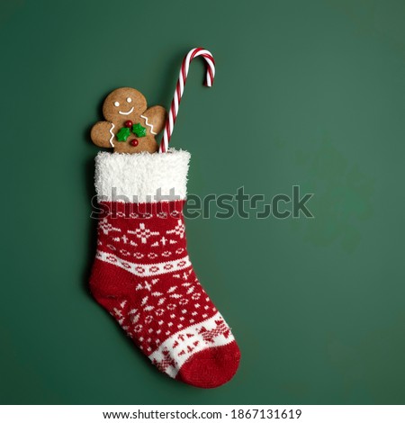 Creative layout made with Christmas socks, gingerbread man and candy cane on green background. Minimal New Year season concept. Top view, flat lay.