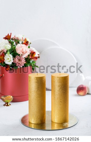 Gold candles, flower arrangement with roses. White background.