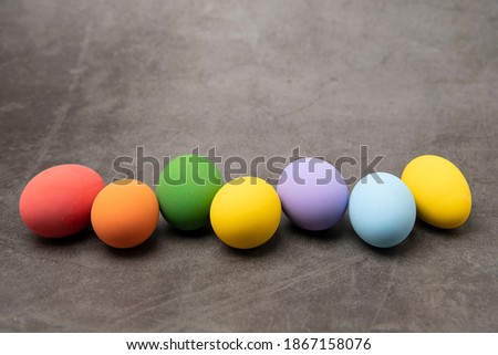 Several colored eggs are placed on the gray table background.