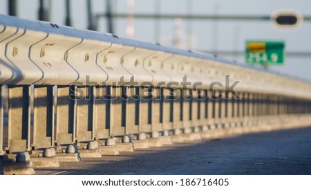 Guard rail or guardrail, sometimes referred to as guide rail or railing, is a system designed to keep people or vehicles from straying into dangerous or off-limits areas. Royalty-Free Stock Photo #186716405