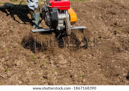 Banner. Man Farmer plows the land with a cultivator. Agricultural machinery: cultivator for tillage in the garden,motor cultivator.