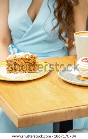 Sweet different pieces of cake on the plates at the table on a woman's background with a cup of coffee in a cafe