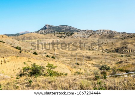 Steppe, hills and mountains in Crimea near the town of Sudak. Telecommunication poles. Sunny cloudless weather Royalty-Free Stock Photo #1867204444