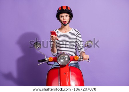 Photo of confused upset lady ride scooter hold telephone open mouth wear helmet striped shirt isolated violet color background