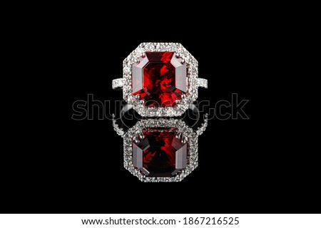 beautiful gold ring with gemstones garnet and diamonds on a black background close-up Royalty-Free Stock Photo #1867216525