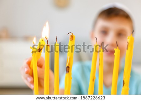Happy boy lighting candles for celebrating Hannukah at home