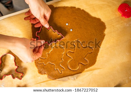 Cutting of gingerbread shapes. A young woman cuts gingerbread shapes on bruna baking paper.