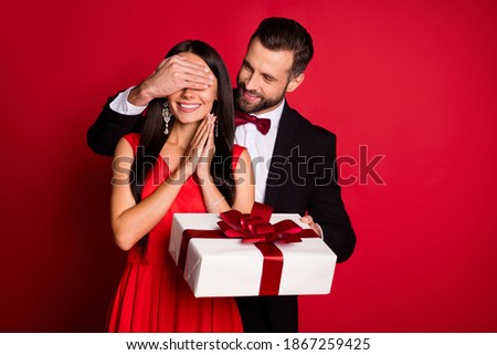Photo of nice optimistic couple man close eyes hold gift wear suit dress isolated on red color background
