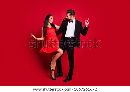 Full size photo of optimistic couple dance wear vivid dress black suit isolated on red color background