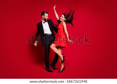 Full size profile photo of optimistic funky couple dance wear vivid dress black suit isolated on red color background