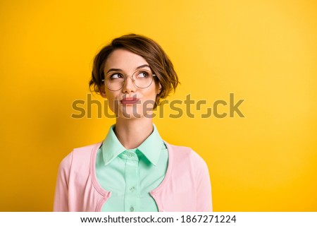 Photo of intelligent girl look up empty space wear spectacles teal shirt pink cardigan isolated yellow color background