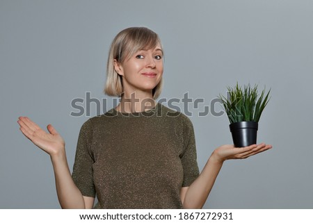 woman with an artificial flower in her hand against the background of a gray wall.