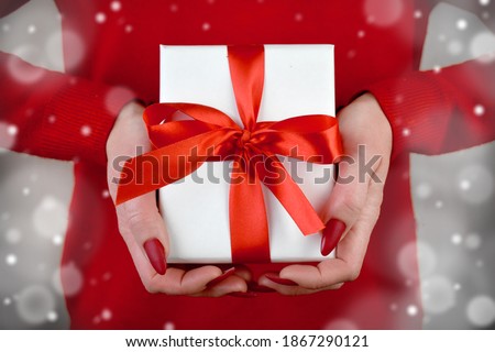 Close up woman's hands holding gift box. Snowy effect Greeting card for Christmas, New year or Valentines day.