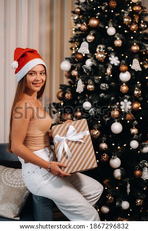 A girl with a toy in her hands stands at home near the Christmas tree