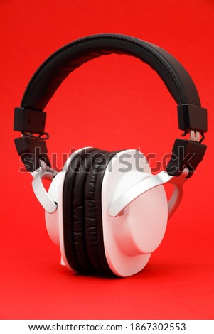Modern black and white headphones isolated on red background. 