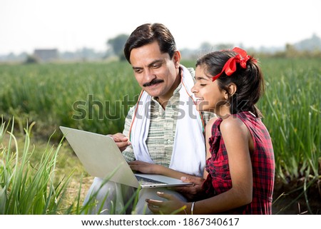 Farmer with daughter using laptop on agriculture field