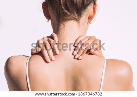 Closeup shot of woman from back having neck or shoulder pain. Injury or muscle spasm. Back and spine disease. Female massaging her neck. Health care and medical concept Royalty-Free Stock Photo #1867346782