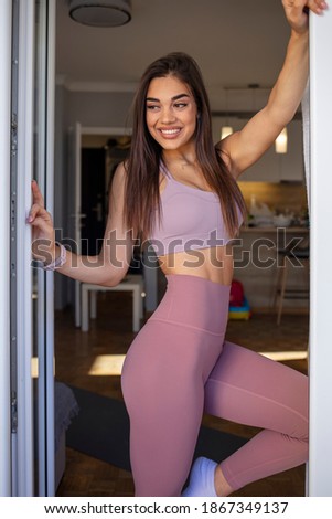 Sporty young woman with muscular body, posing. Healthy female model standing. Shot of a healthy-looking young woman. Sport, fitness and people concept - young woman in purple sportswear posing
