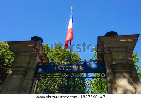 The gate at the entrance of the Prefecture of Tarn Department, framed between two stone pillars, overhung by a flag of France on top of its mast ; the Prefect of Tarn is headquartered in Albi Royalty-Free Stock Photo #1867360147