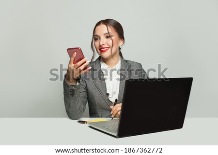Happy businesswoman with laptop and phone sitting in office